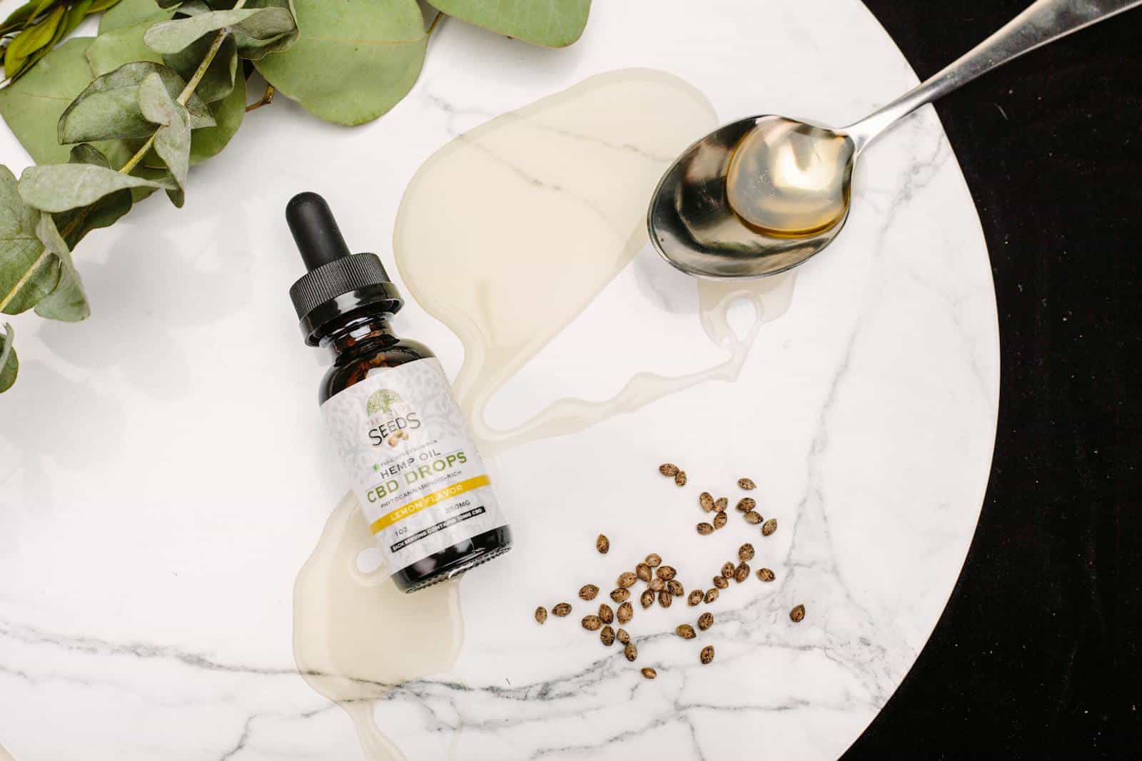 CBD oil drops with seeds and eucalyptus leaves on marble. Perfect for health and wellness themes.