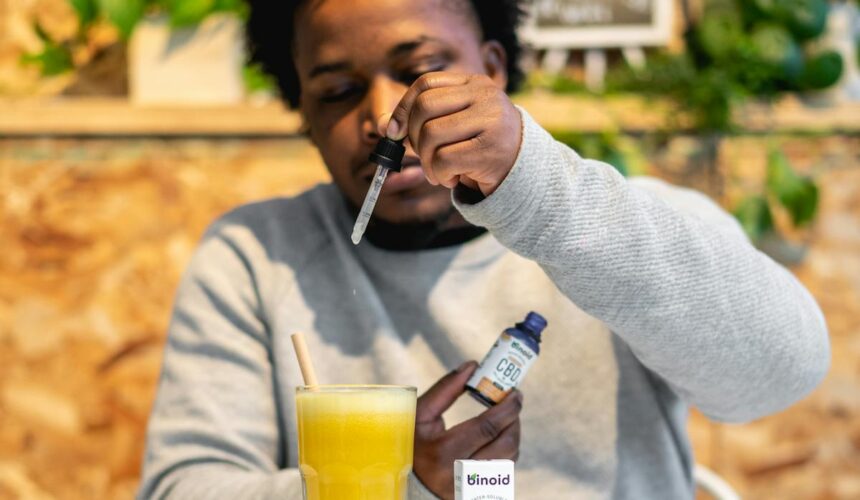 Man mixing CBD tincture into orange juice for a healthy lifestyle indoors.