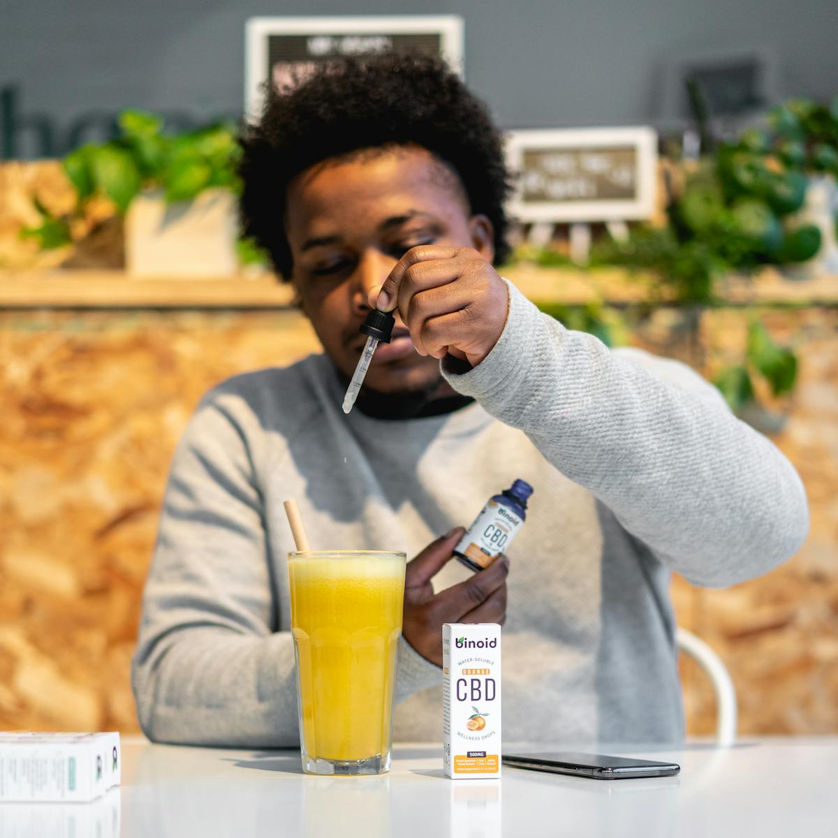 Man mixing CBD tincture into orange juice for a healthy lifestyle indoors.