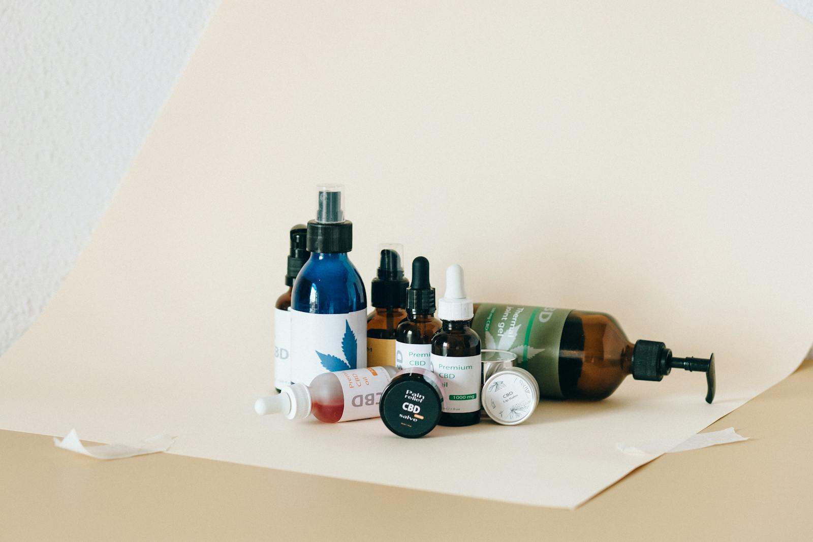 Une collection de produits CBD comprenant des huiles et des sprays dans une configuration de studio avec un fond neutre.